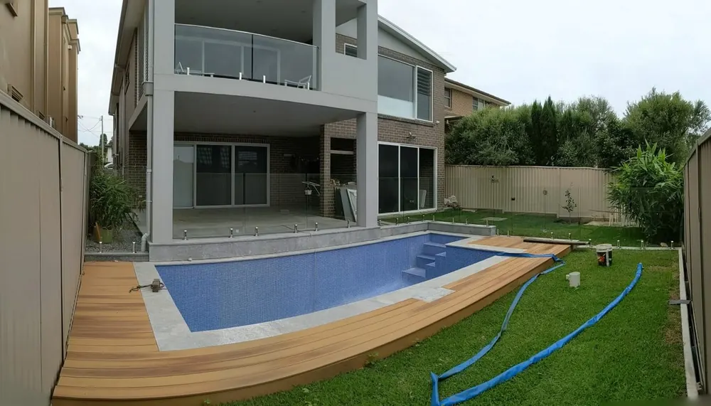 Frameless glass pool fence around a landscaped backyard pool